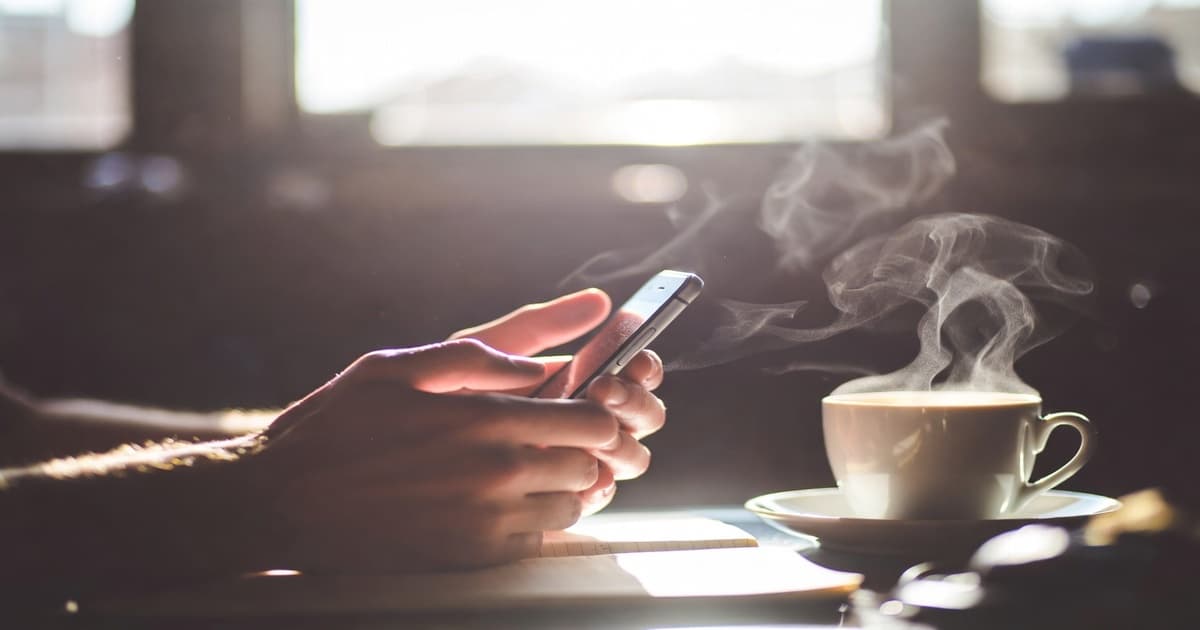 A pair of hands composing a thoughtful response on a phone in soft light