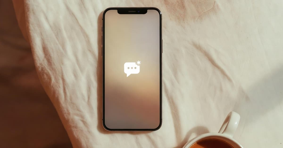 An overhead view of a phone resting on a soft neutral surface with an unread message
